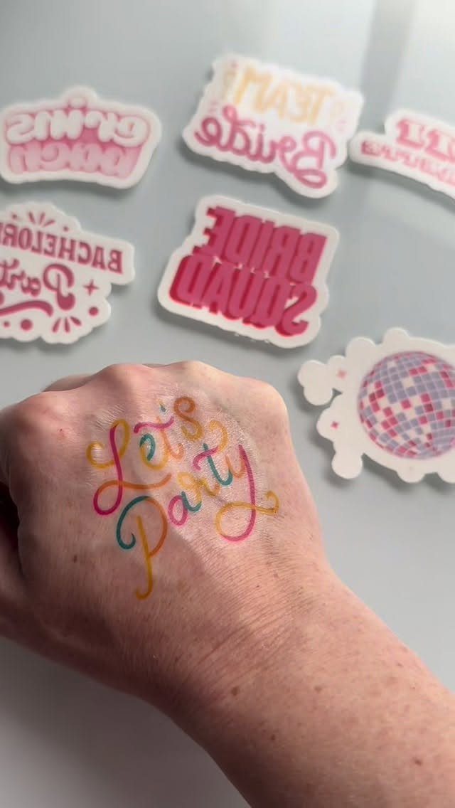Hand with Let's Party tattoo surrounded by various pink wedding temporary tattoo designs.