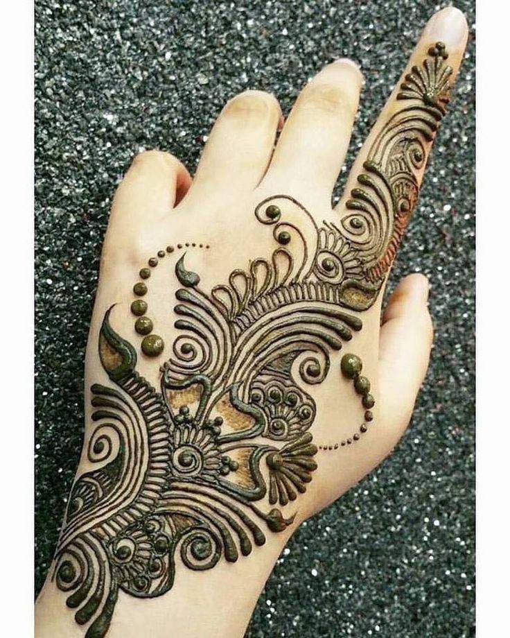 Intricate brown henna tattoo design on a hand against a silver glitter background
