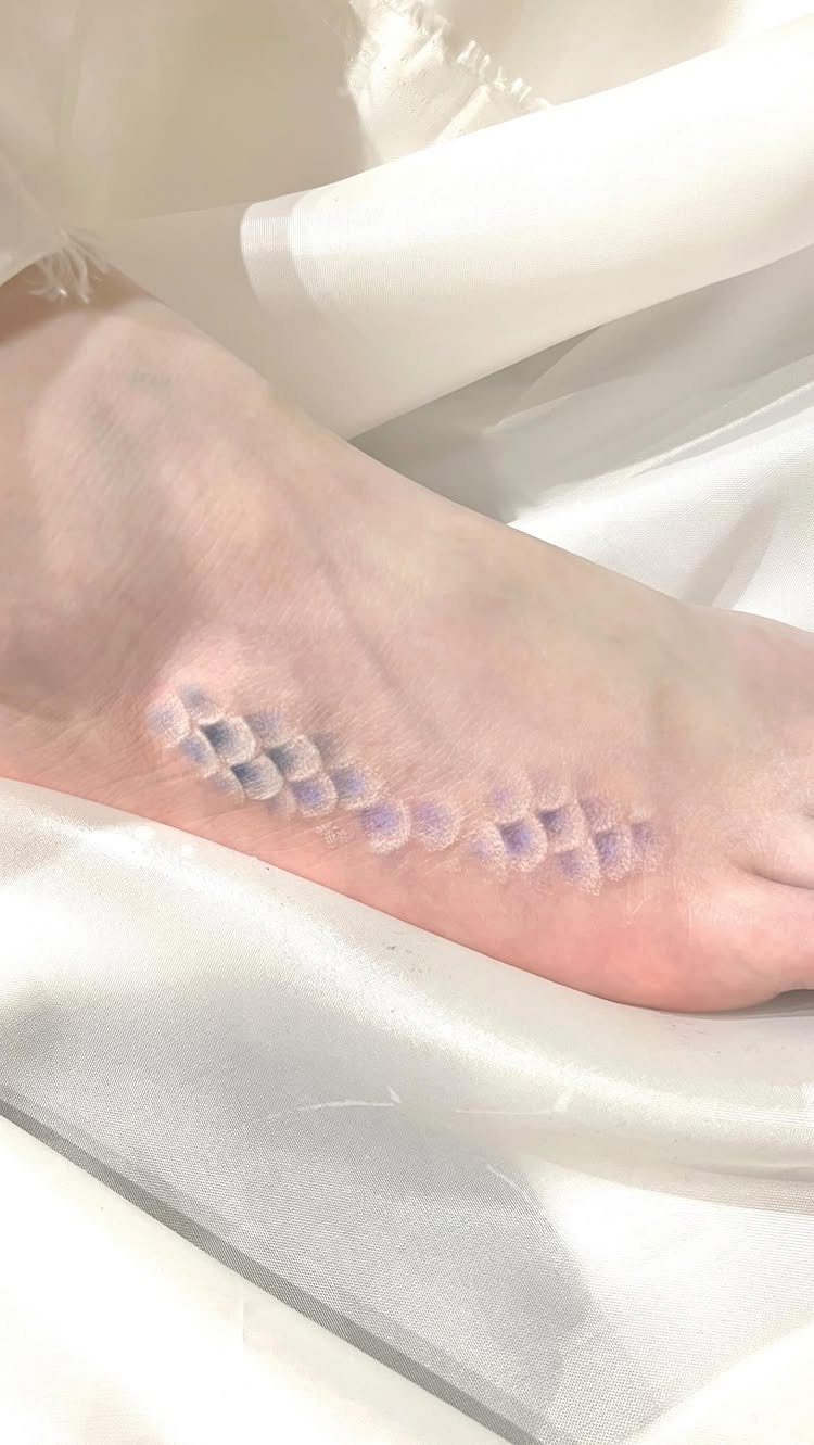 White ink tattoo of fish scales on the side of a human foot