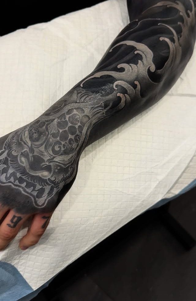 Foot and ankle with dark skin featuring white ink tattoo highlights in swirls